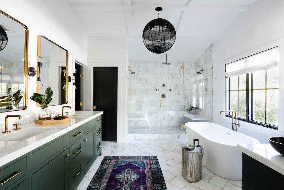 primary bath with green vanity and freestanding tub