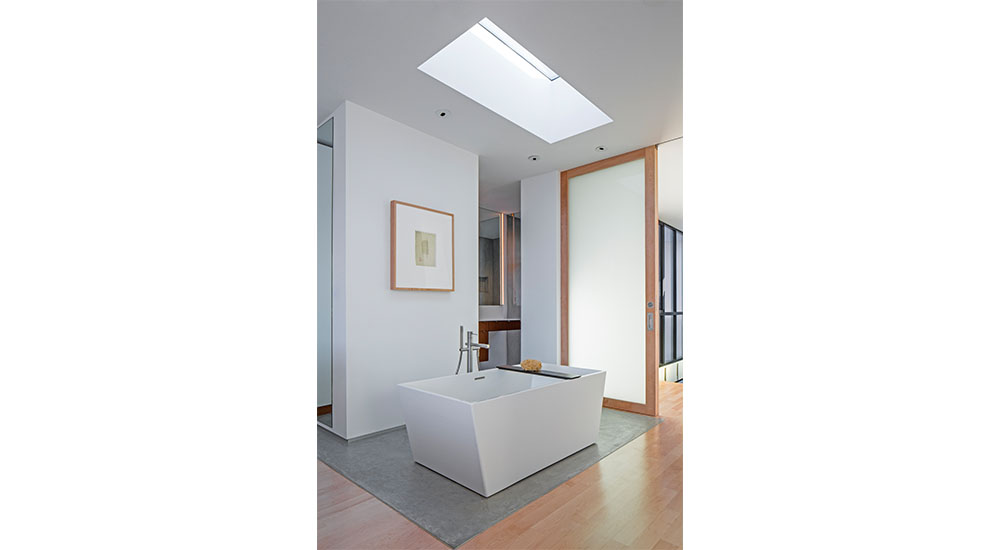 spa bathroom design trends freestanding tub under skylight in primary suite