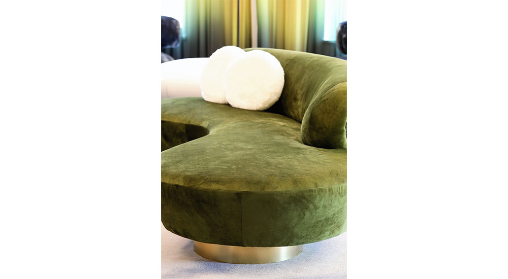 curving sofa upholstered in green velvet