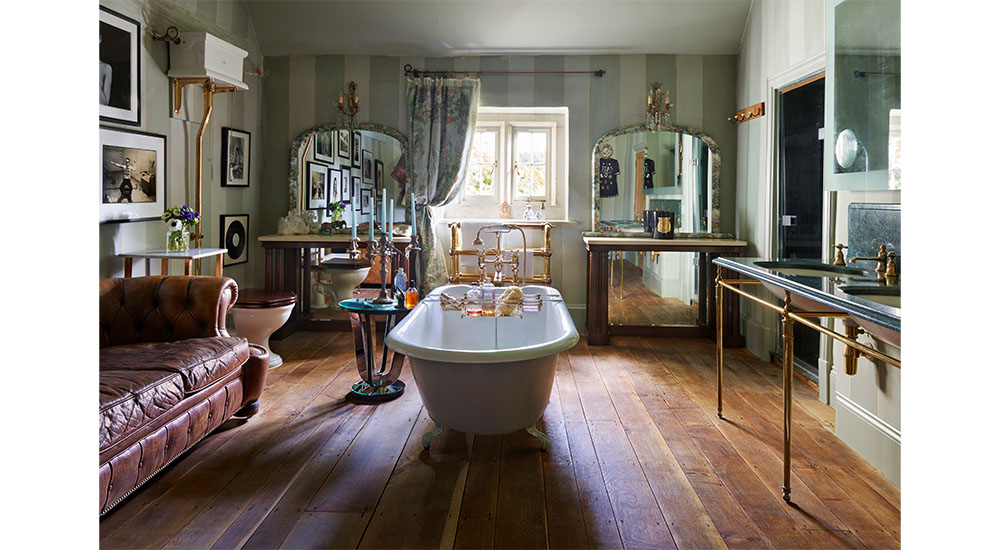 bathtub in middle of room with leather sofa and fireplace